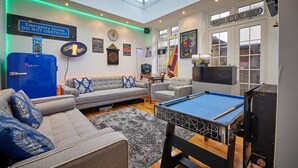 A modern living room with a pool table, sofas, and a blue refrigerator. - Host & Stay | The View Old Coastguard Cottage (North Shields)