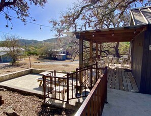 A covered outdoor patio with wooden railings, plastic chairs, and tables.