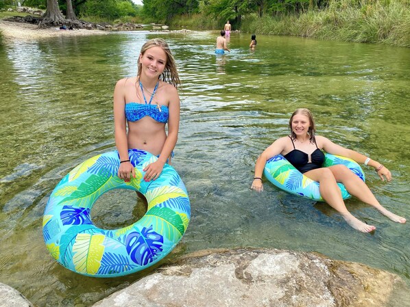 Two people sitting on inflatable rings in a river.