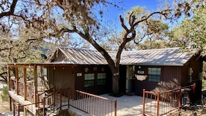 A rustic cabin with a wooden deck and a metal staircase leading to a porch. - Sweet Riverside Cabin, Easy Walk 2 River, Private River Access, River Views! (Concan)