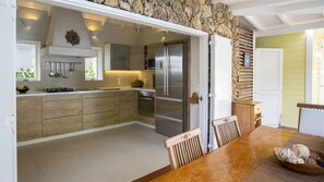 Een moderne keuken met een stenen muur, roestvrijstalen apparatuur en een houten eettafel.