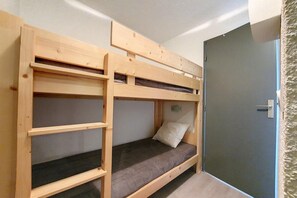 Habitación con literas, una puerta y un estante pequeño.