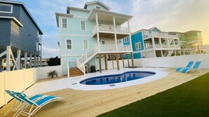 A multi-story beachfront house with a swimming pool and deck chairs. - 1030 Ocean 5 Bedroom Home by RedAwning (Supply)