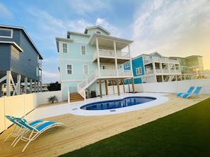 Uma casa à beira-mar de vários andares, com piscina e espreguiçadeiras.