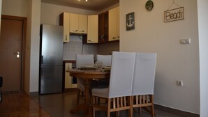 A compact kitchen with a refrigerator, wooden cabinets, and a dining table with chairs. - Romantic comfortable apartment (Trogir)