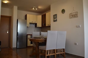 A compact kitchen with a refrigerator, wooden cabinets, and a dining table with chairs. - Romantic comfortable apartment (Trogir)