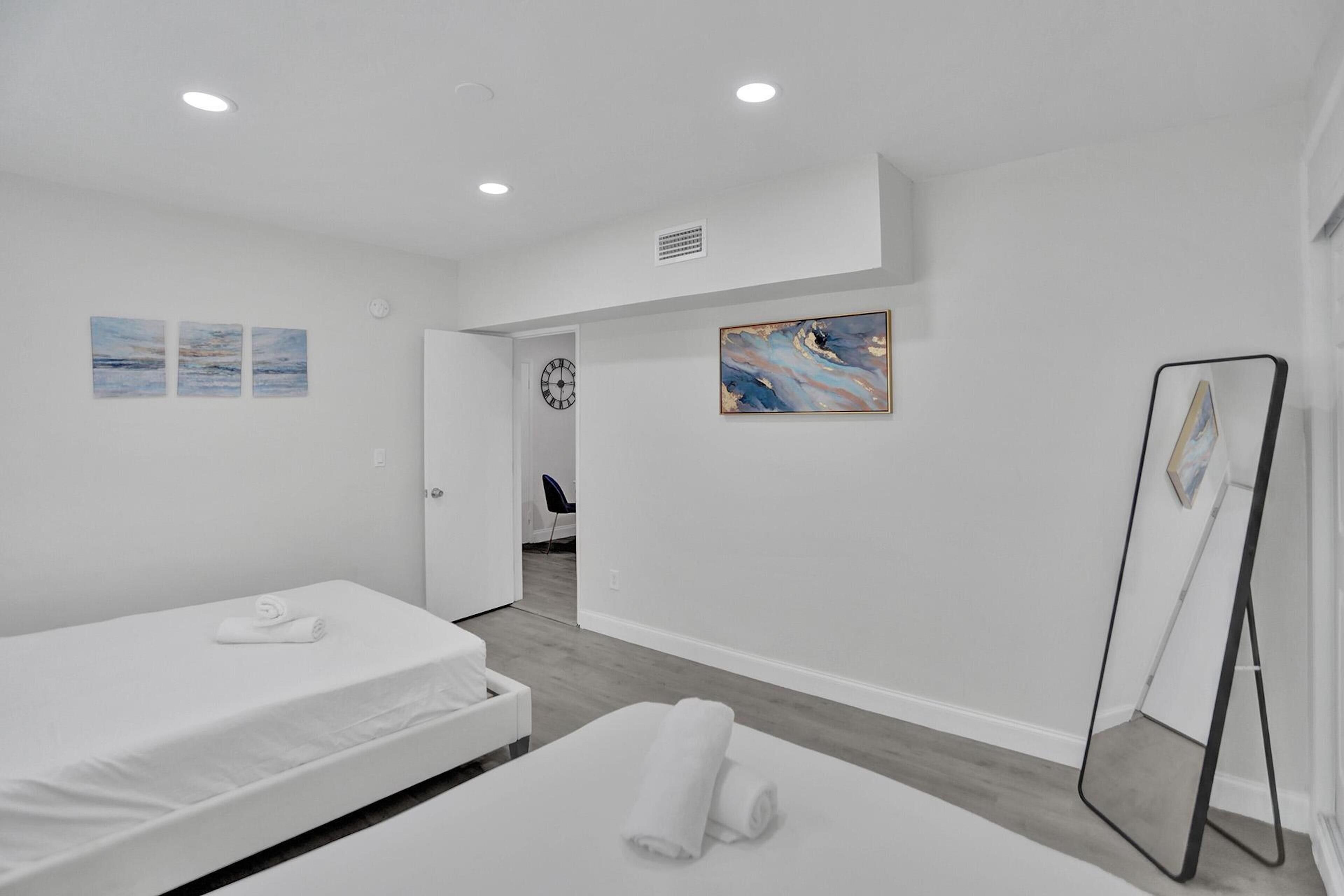 Una habitación de hotel con una cama, una mesita de noche, un espejo y obras de arte en las paredes.