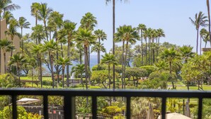 A lush tropical garden with tall palm trees and a view of the ocean.