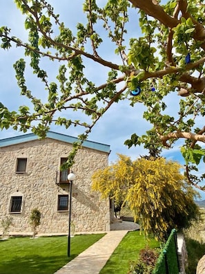 A stone building with a sloped roof, a paved pathway, and a well-maintained lawn. - Vista Garden Datca (Datça)
