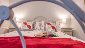 A neatly made bed with a red blanket, floral pillows, and a bedside table with a lamp. - 2 Riverside Cottages, Yoxford (Saxmundham)