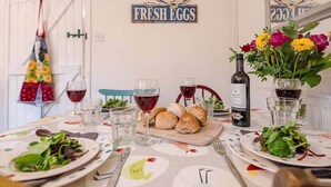 A dining table set with plates, glasses, a bottle, and a bouquet of flowers. - 2 Riverside Cottages, Yoxford (Saxmundham)