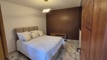 A bedroom with a bed, wooden panel wall, and marble flooring.