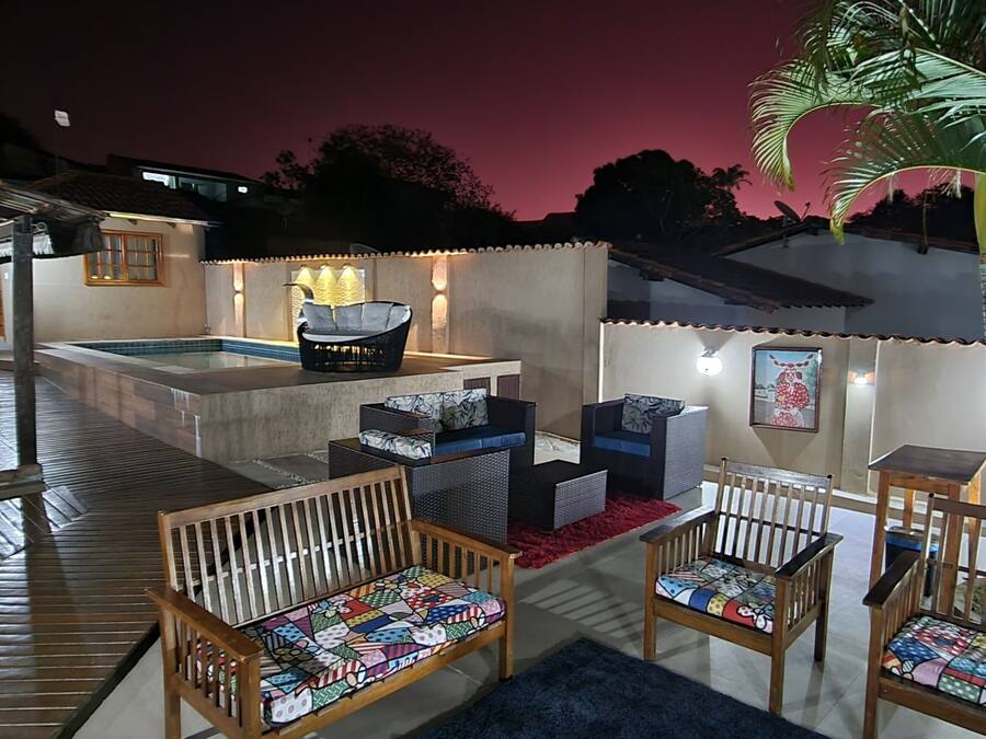 Un patio al aire libre con mobiliario de madera, una piscina y un ambiente bien iluminado.