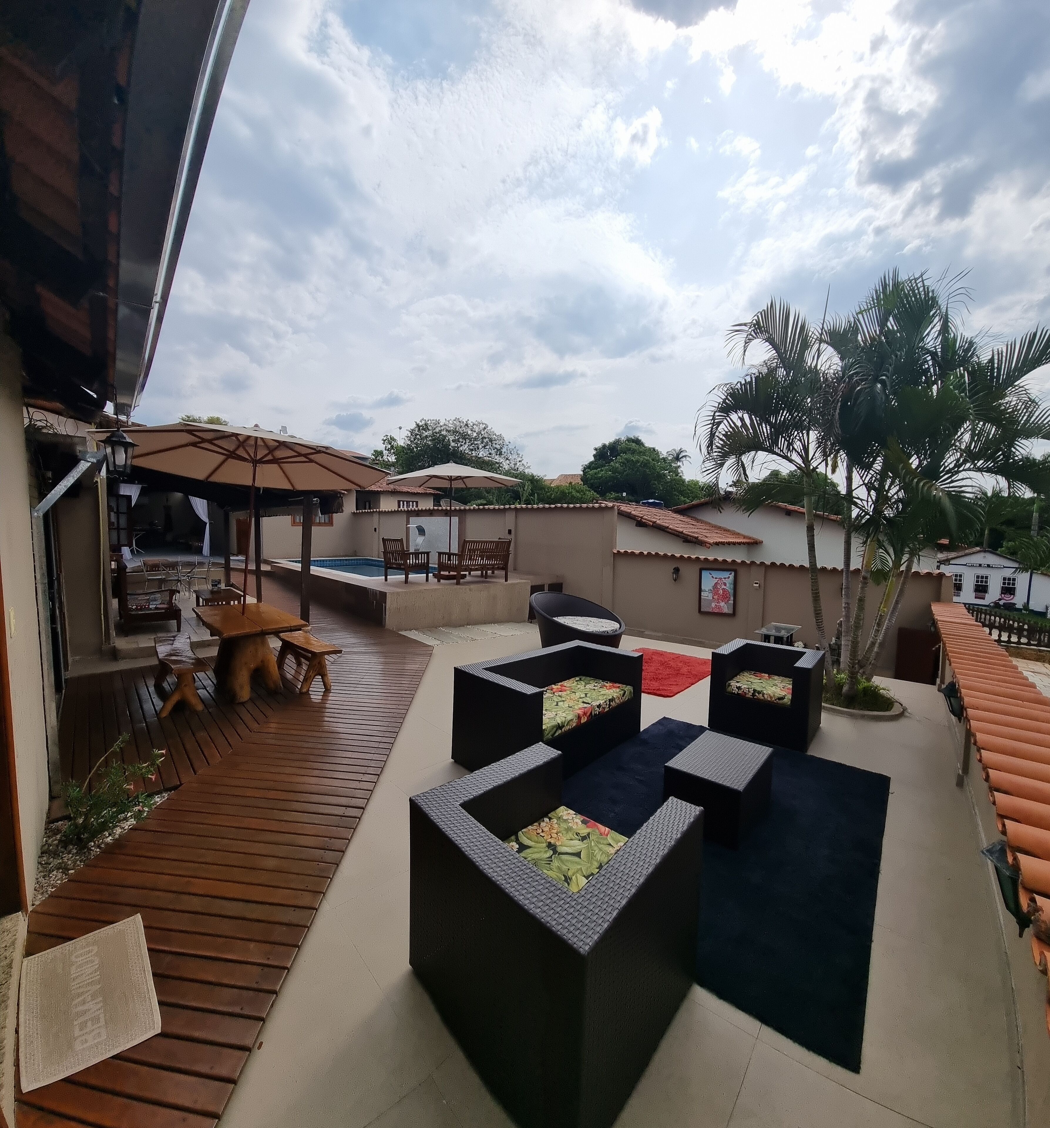 A rooftop patio with wooden flooring, outdoor seating, and a pool.
