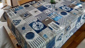 Cocina compacta con refrigerador, microondas y estufa. Hay una mesa de comedor con mantel estampado y una planta en maceta.