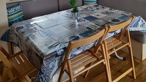 Una habitación acogedora con un ventanal grande, un sofá, una mesa de comedor y un banco de madera.