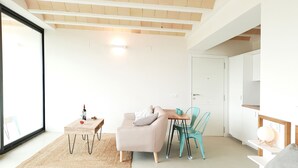 A modern, well-lit room with a bed, a sofa, a dining table with chairs, and a large window. - Estrellas de Gredos (Arenas de San Pedro)