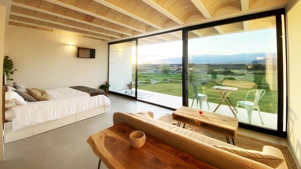 A modern bedroom with a large sliding glass door leading to a balcony with a view of a green landscape. - Estrellas de Gredos (Arenas de San Pedro)