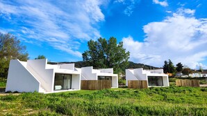 A modern, white, two-story house with a flat roof and large windows, surrounded by lush greenery and a clear blue sky. - Estrellas de Gredos (Arenas de San Pedro)