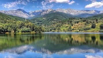 Un lago sereno con montañas al fondo y un cielo despejado.