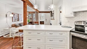 A modern kitchen with white cabinetry, a large island with multiple drawers, a built-in oven, and pendant lighting. - Abbey Springs Condo with Private Patio Pools Beach Fitness and Resort Living (Fontana)