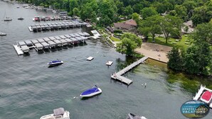 An aerial view of a lakeside property with docked boats, a marina, and a beach area with picnic tables. - Abbey Springs Condo with Private Patio Pools Beach Fitness and Resort Living (Fontana)