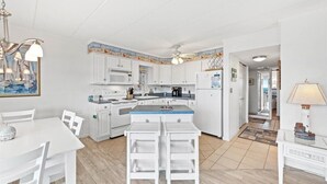 Une cuisine moderne avec des meubles blancs, un îlot central et un coin repas avec des chaises blanches.