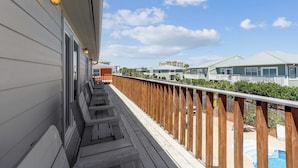 A wooden deck with a railing, a pool, and a view of neighboring houses. - Magnolia by the Sea- 5 BR Home with Private Pool on Holiday Isle (Destin)