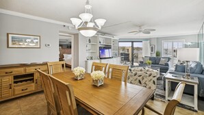 Amplia sala de estar con una mesa de comedor de madera, un sofá y un televisor.