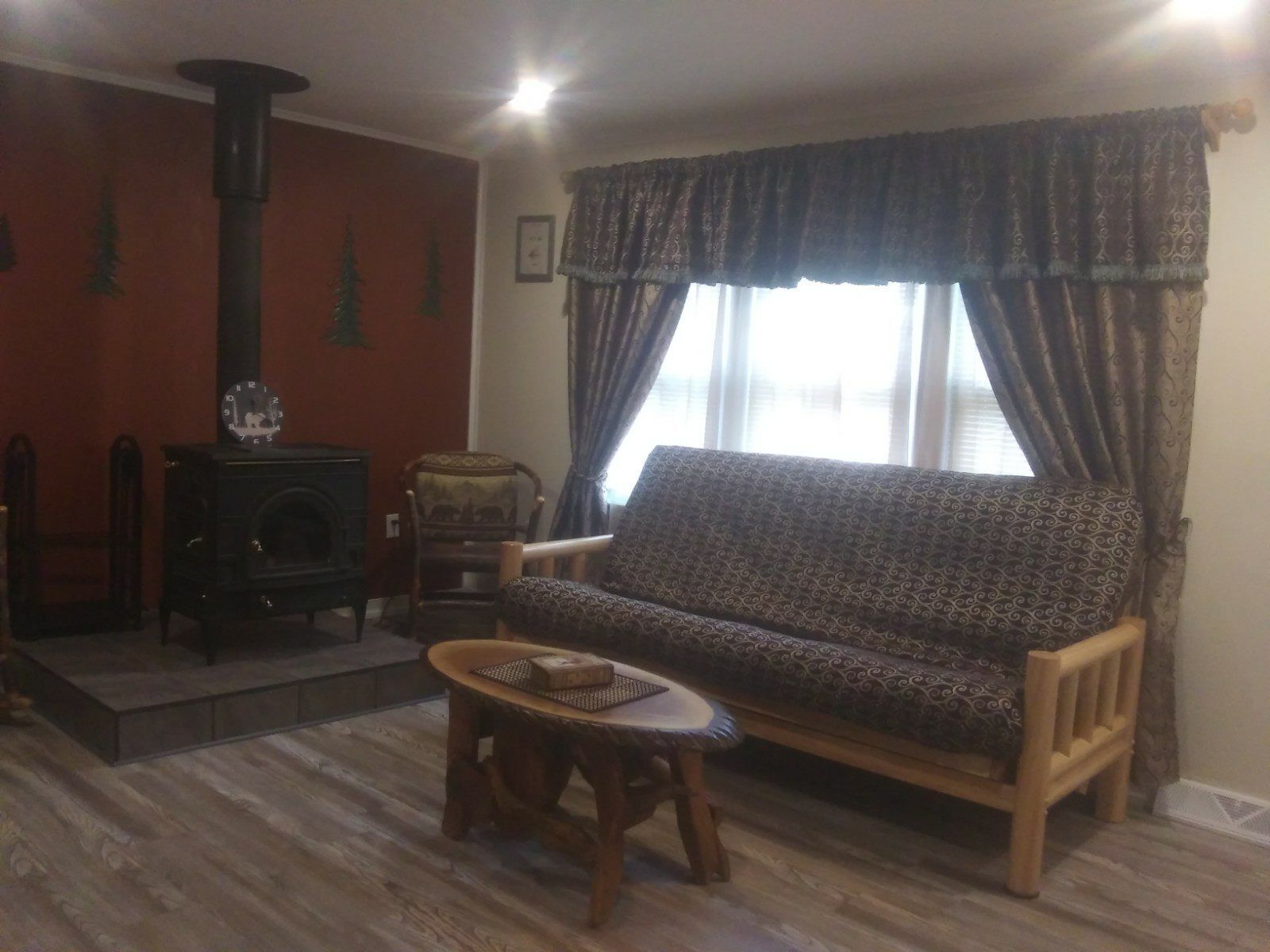 Un salon avec un canapé, une petite table, une cheminée et une fenêtre avec des rideaux.