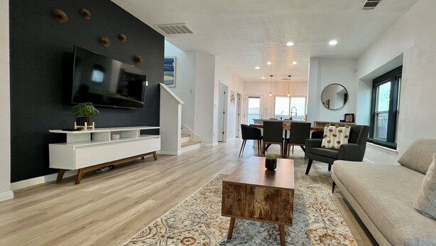 A modern living room with a flat-screen TV, a wooden coffee table, and a patterned rug.