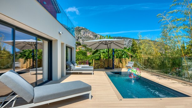 A modern outdoor pool area with lounge chairs, umbrellas, and a view of a mountainous landscape. - VILLA GRAZIELLA 200 M FROM THE BEACH (Èze)