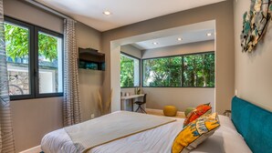 A bedroom with a large bed, a desk, and a view of greenery through the windows. - VILLA GRAZIELLA 200 M FROM THE BEACH (Èze)