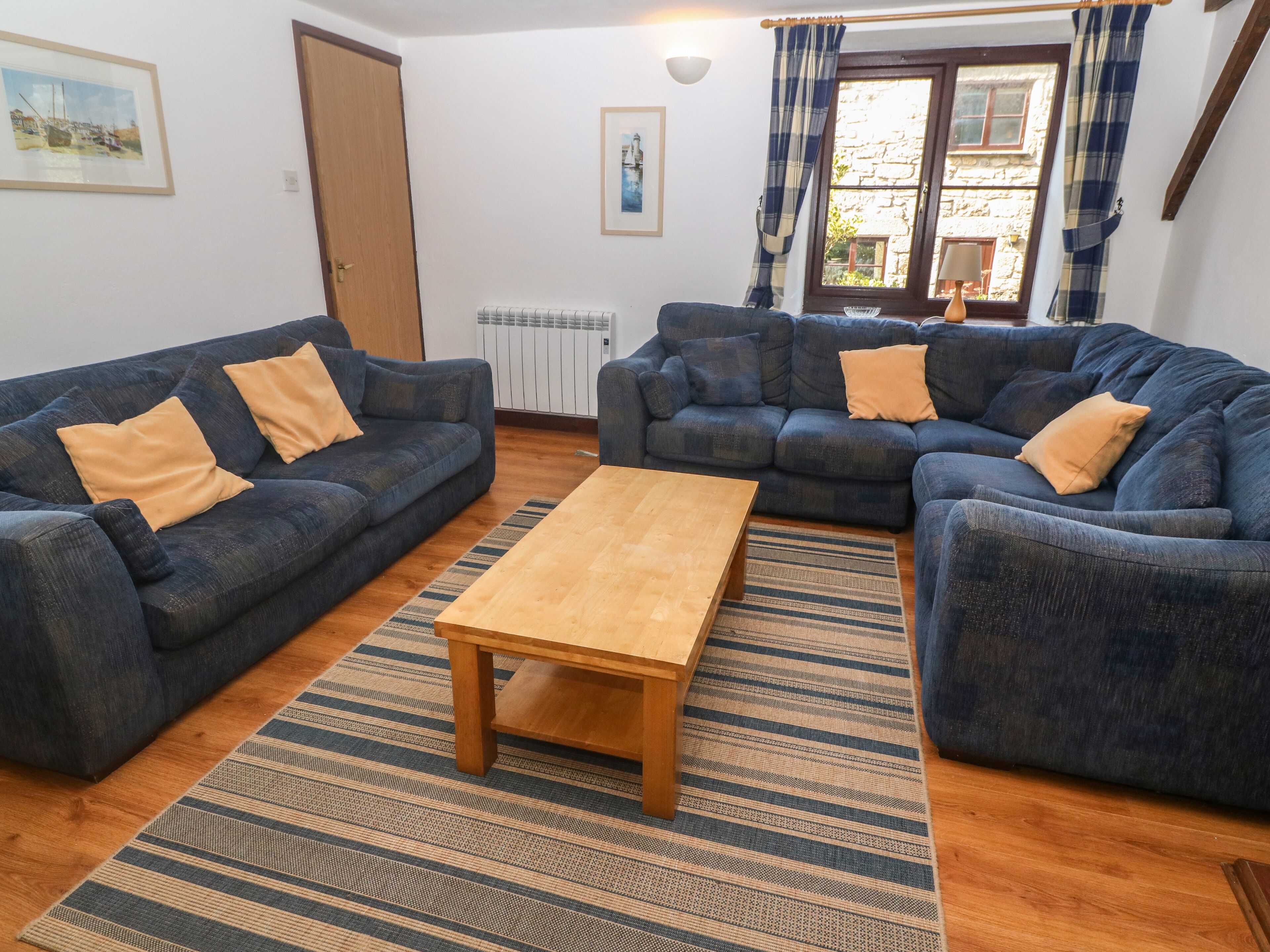 A living room with two blue sofas, a wooden coffee table, and a striped rug.