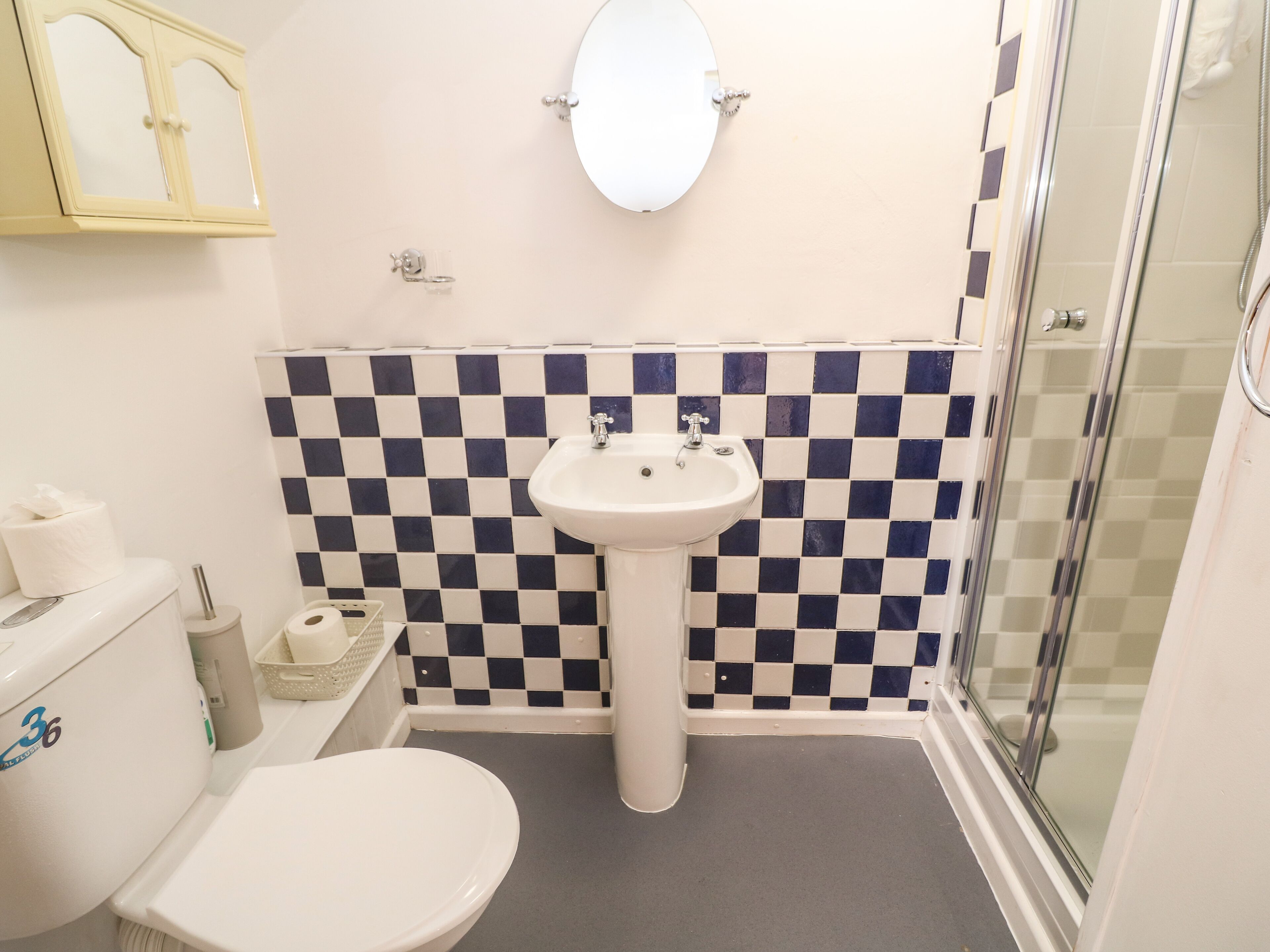 Une salle de bain avec un mur recouvert de carreaux à motifs, un lavabo sur pied, des toilettes et une douche en verre.