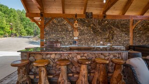 Un coin bar rustique avec un mur en pierre, des tabourets en bois et une cheminée en pierre.