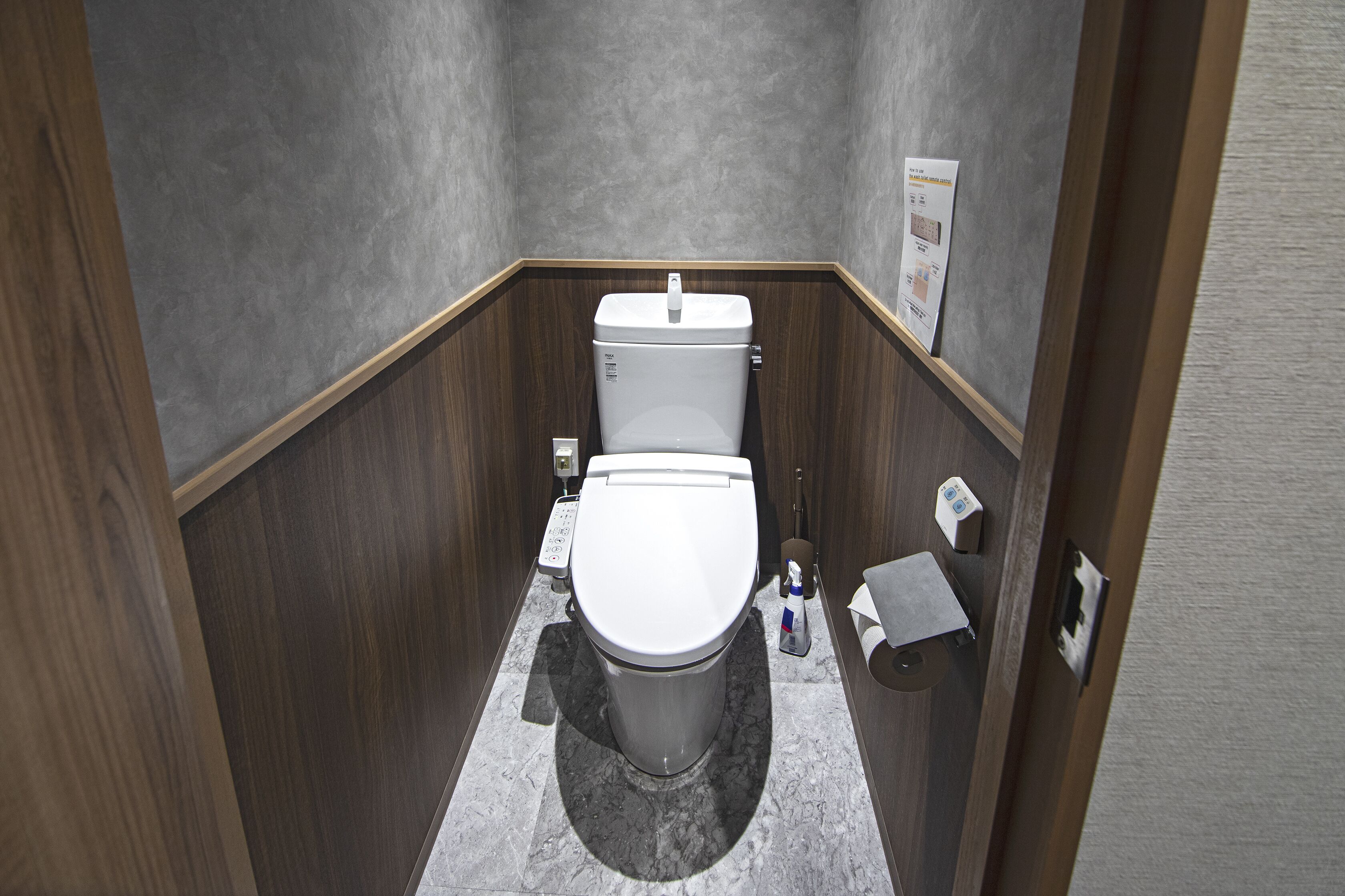 Une petite salle de bain équipée de toilettes, d’un sèche-mains et d’un distributeur de serviettes en papier.