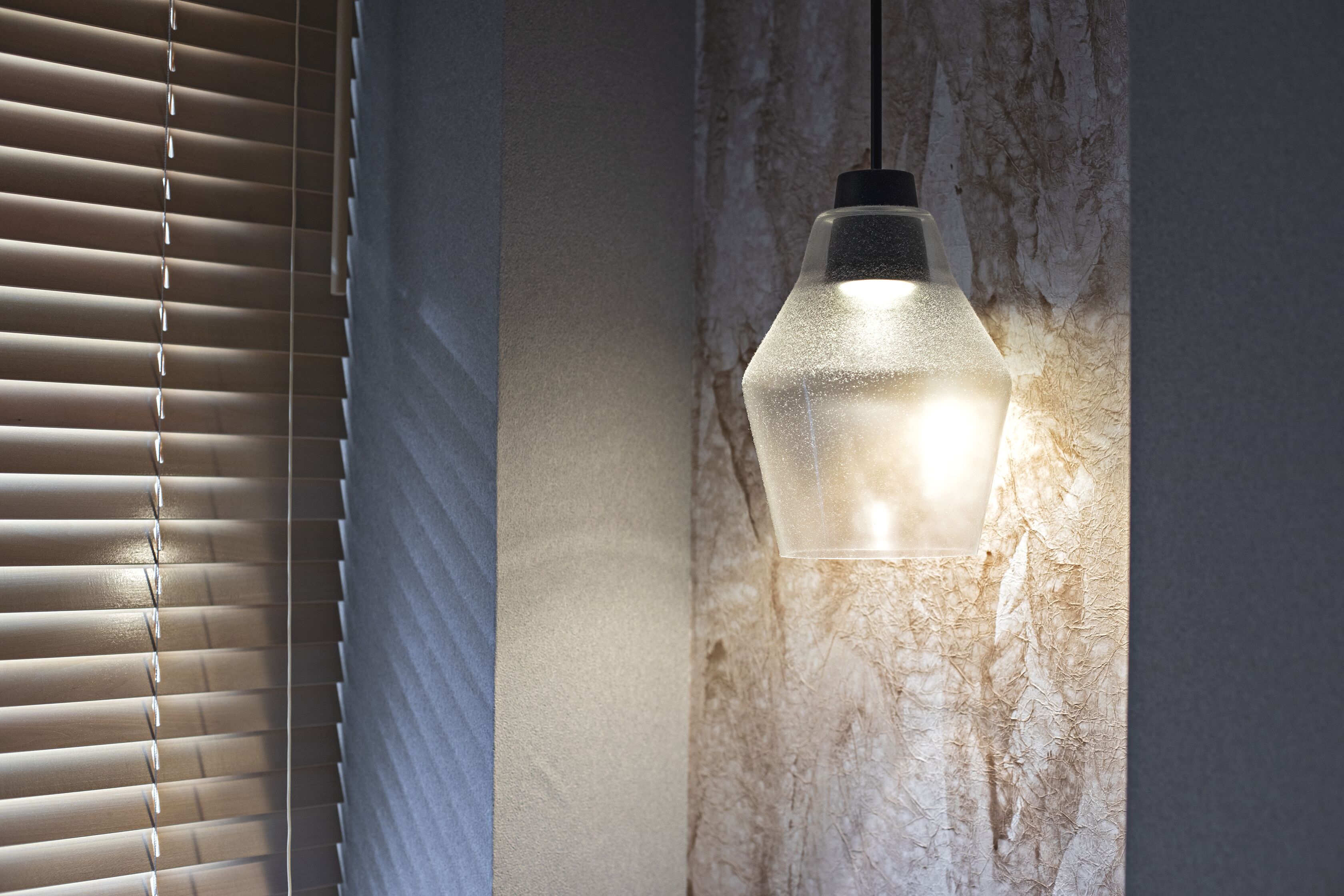 A room with a textured wall and a hanging light fixture.