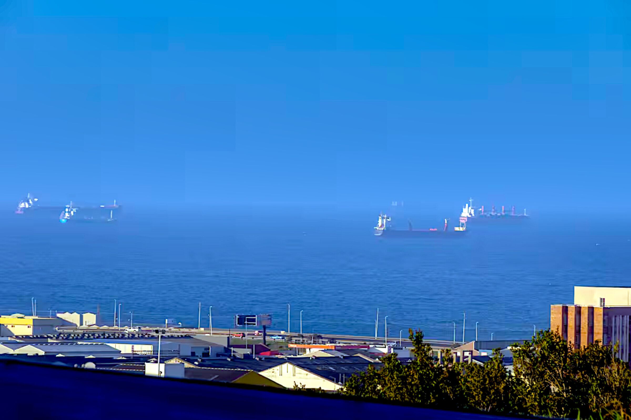 A coastal view with a marina, several boats, and buildings along the shore.