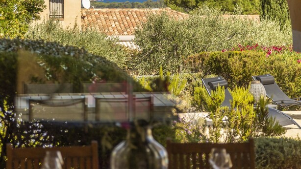 A dining area with a table set for two, overlooking a scenic view of the sea and a garden with olive trees. - Exceptional villa with magnificent sea view and swimming pool (Calvi)