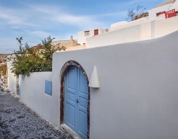 A white-walled building with a blue door and a small window.