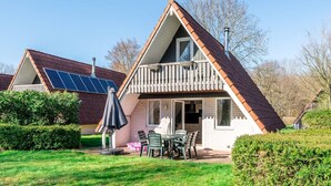 Ein haus mit Giebeldach, einem Balkon, Solaranlage und einer Terrasse mit Stühlen und Tisch.