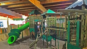 Ein Spielplatz mit Rutsche, Klettergerüsten und Netzbereichen.