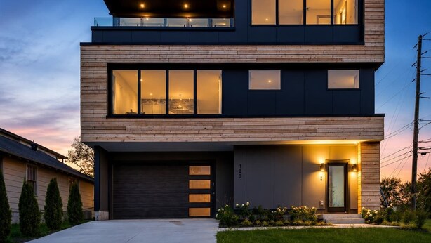 Una casa moderna de dos plantas con garaje, ventanas amplias y una entrada bien iluminada.