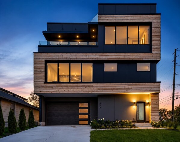 A modern two-story house with a garage, large windows, and a well-lit entrance. - Modern Stunner! Rooftop Views,5 min to DT,Hot Tub (Nashville)