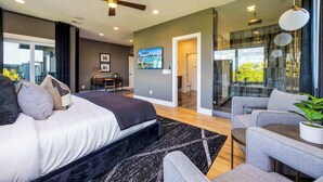 Un dormitorio moderno con una cama grande, un escritorio y una zona de estar con vistas al exterior.