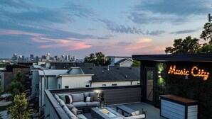 Una terraza en la azotea con un sofá, una mesa de centro y un letrero de neón que dice 'Music City'.