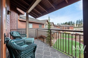 Enjoy a peaceful view of the neighborhood from this balcony with two chairs and a table.