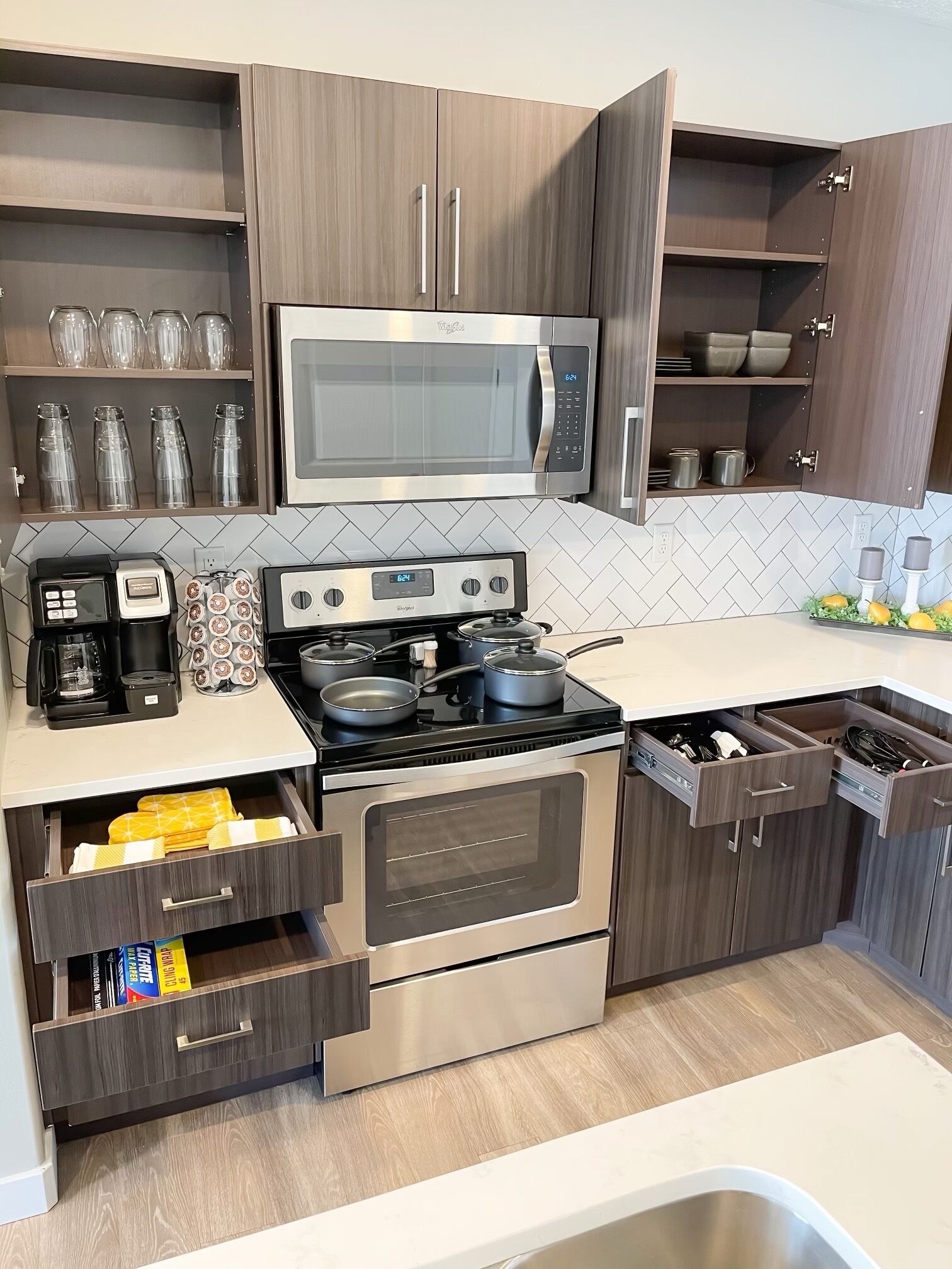Una cocina moderna con armarios de madera oscura, una estufa de acero inoxidable, un microondas y una cafetera.