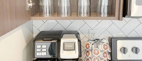 Una cocina con cafetera, tostadora y repisas con frascos de vidrio.